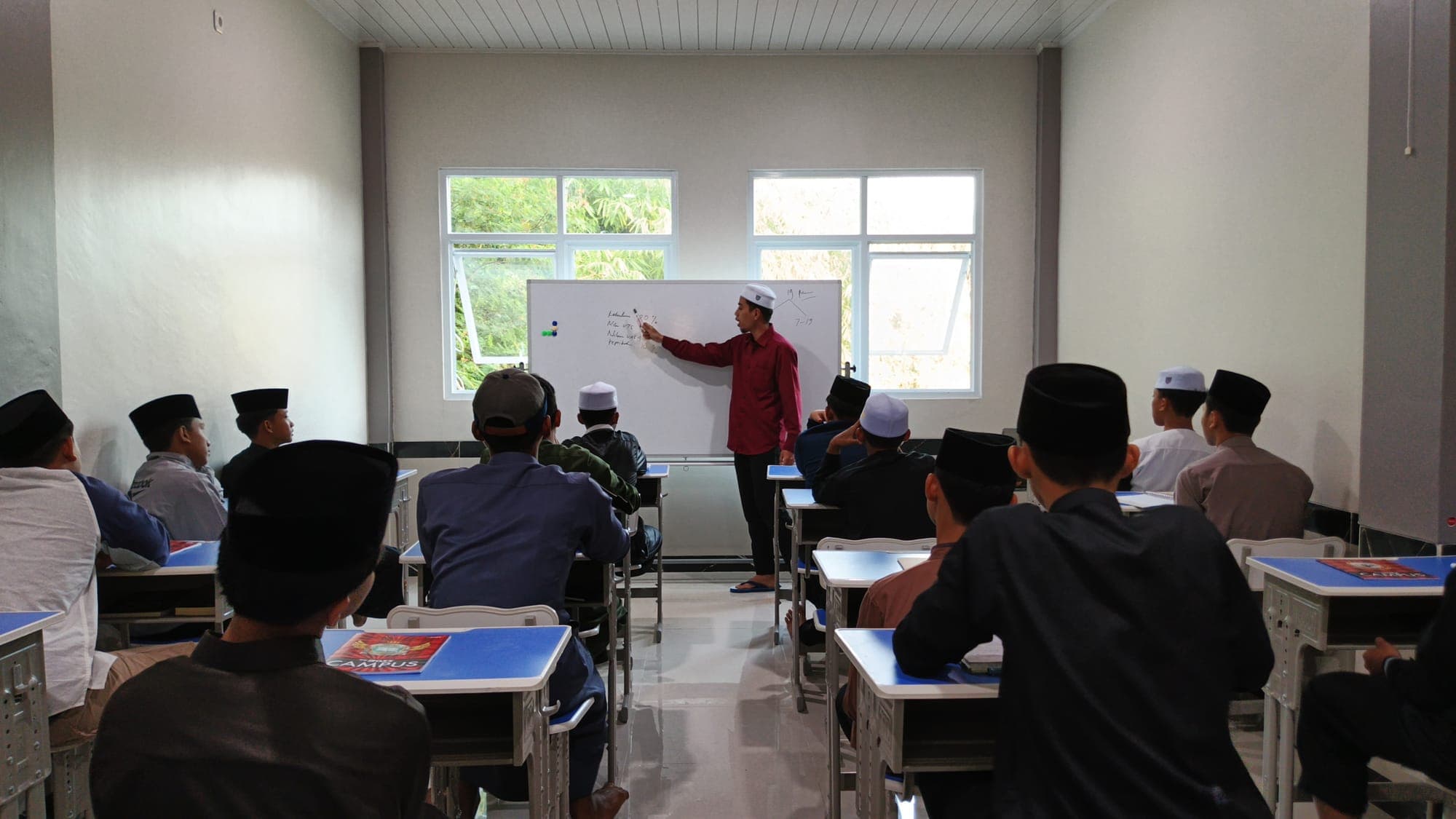 Ustadz menerangkan materi di papan tulis di hadapan santri MTs dan MA Wadi Mubarak