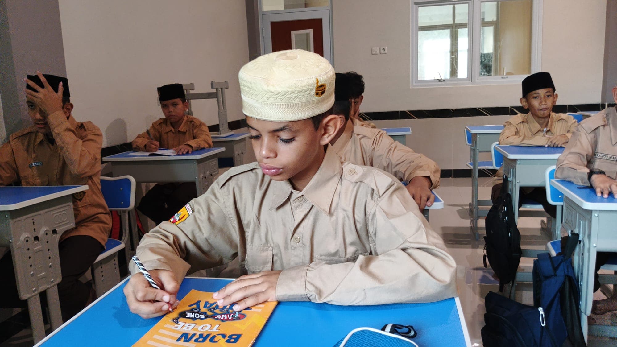 Santri MTs dan MA Wadi Mubarak berseragam pramuka menulis di bukunya saat pelajaran berlangsung
