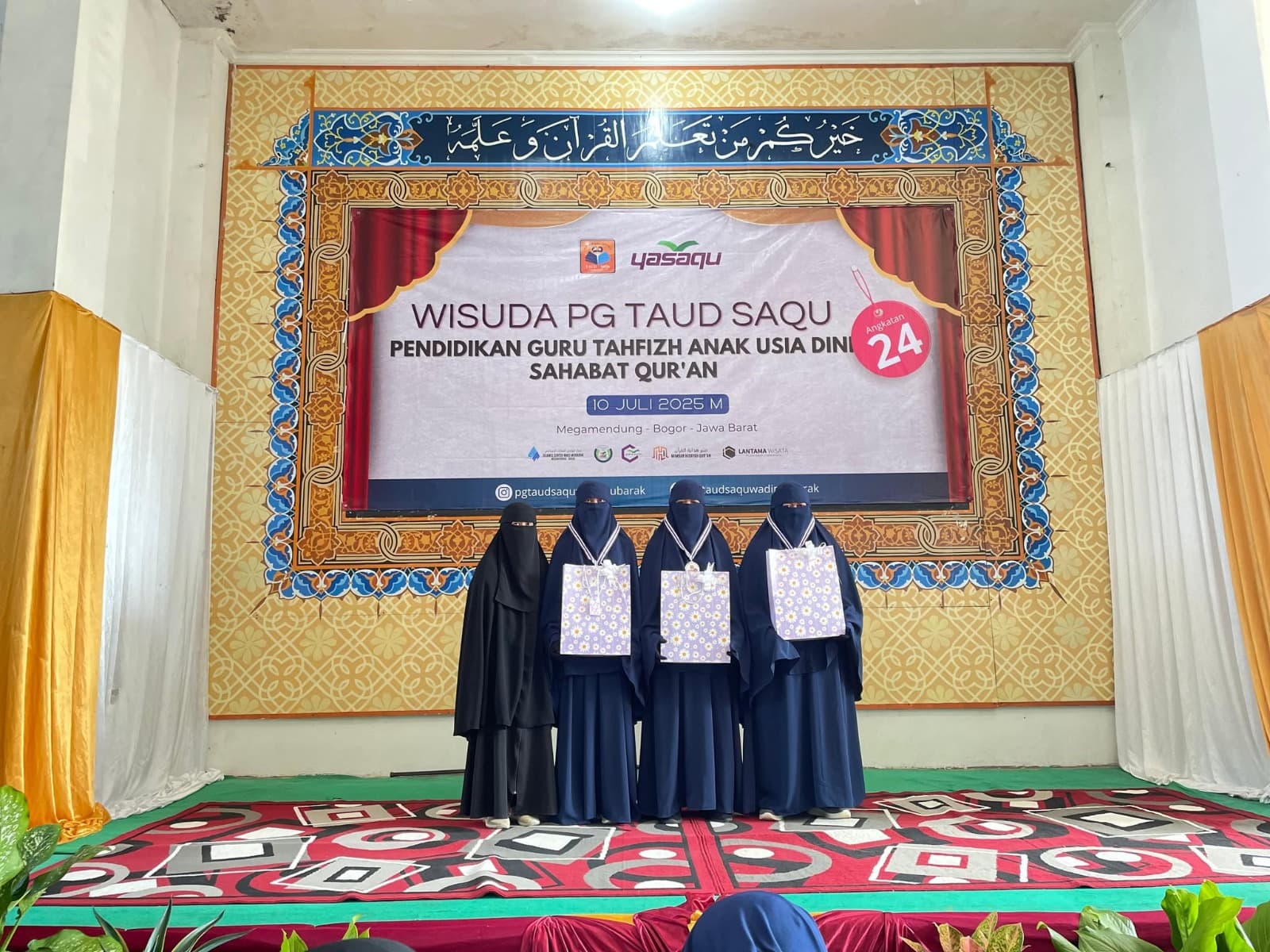 Wisudawati PG TAUD SAQU menerima cendera mata di panggung wisuda